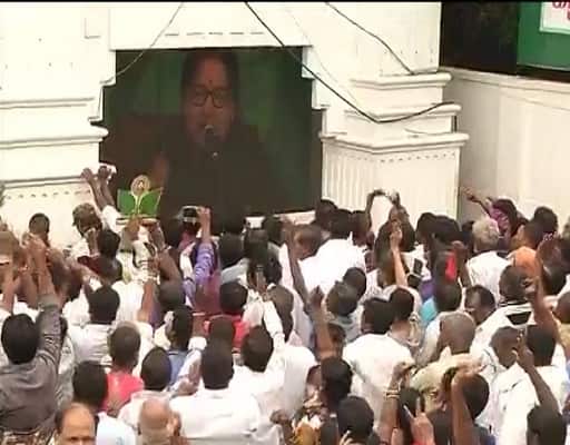 People celebrating AIADMK's win in front of Jayalalithaa's poster