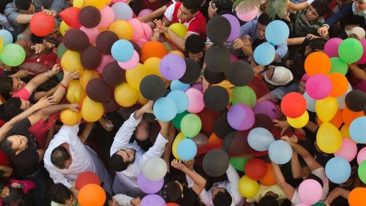 People in Egypt try to catch balloons distributed for free during Eid. (Source: AP)