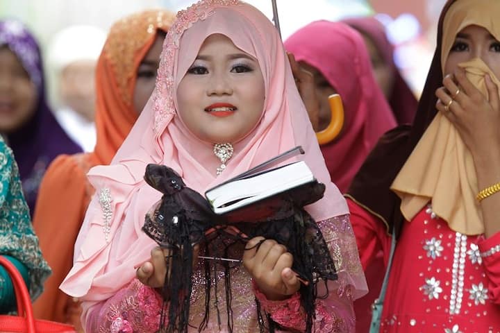 A girl carries a Quran in Cambodia as a part of Eid-al-Fitr Celebrations. (Source: AP)
