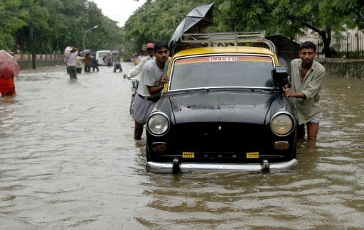 A driver pushes his taxi on a flooded street.