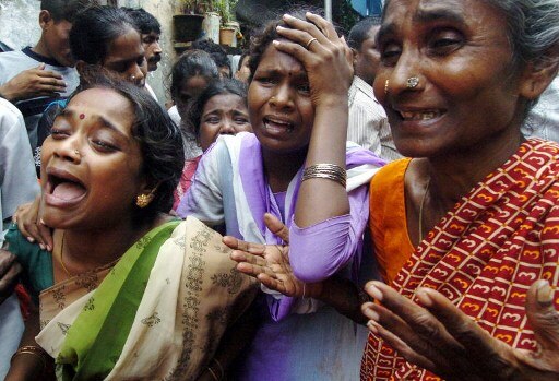 Neighbours and relatives grieve during a funeral of an Indian stampede victim in the Nehru Nagar shantytown in Mumbai 29 July 2005. Residents of a Mumbai shantytown stampeded on false rumours of a burst dam and tsnumai waves advancing towards the coast.