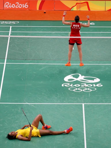 Spain's Carolina Marin, top, celebrates after defeating India's V. Sindhu Pusarla, bottom, in the women's badminton singles gold medal match at the 2016 Summer Olympics in Rio de Janeiro, Brazil, Friday, Aug. 19, 2016. (AP Photo/Vincent Thian)