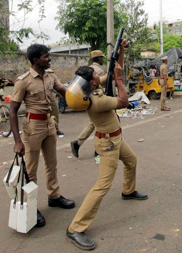 A police man fires tear gas to disperse protestors in Chennai (AP Photo)