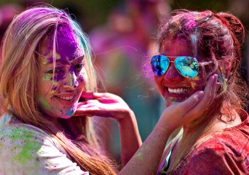 A foreign tourist, left and an Indian smear colored powder on each other as they celebrate Holi, the festival of colors in Hyderabad, India, Sunday, March 12, 2017. Holi, the Hindu festival of colors, also heralds the coming of spring. (AP Photo/Mahesh Kumar A.)