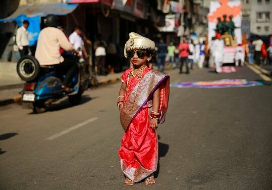 A girl from Maharashtra state dressed in traditional attire poses for photographs during a procession to celebrate