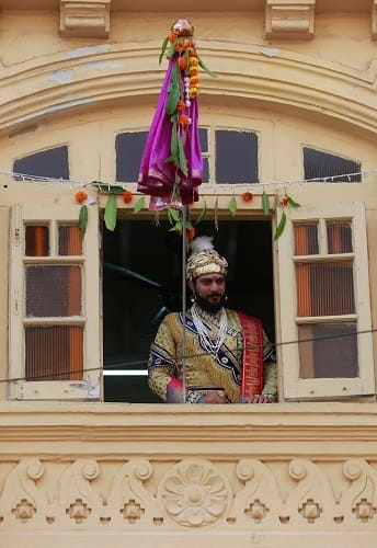 A man dressed in a traditional attire watches a procession to celebrate 
