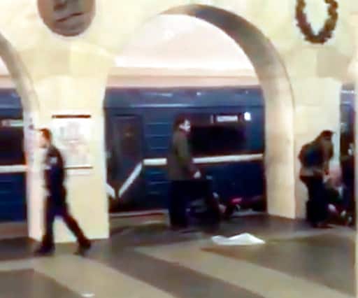 In this grab taken from AP video, Russian police officer, left, and people walk past the damaged train at the Tekhnologichesky Institut subway station in St.Petersburg, Russia, Monday, April 3, 2017. The subway in the Russian city of St. Petersburg is reporting that several people have been injured in an explosion on a subway train. (AP video via AP)