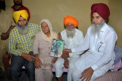 Udham Singh (2-R) and his wife Gurinder Kaur (2-L), hold a picture of their son in their residence in Vein Pein village/ AFP PHOTO
