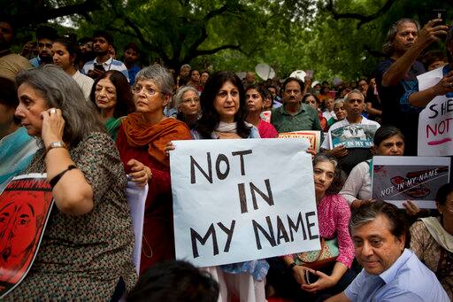 An Indian woman holds placard and listens to a speaker during the protets. PIC/AP.