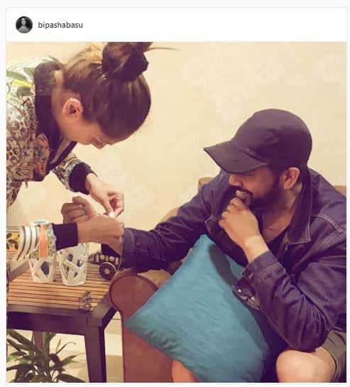 Actress Bipasha Basu tying Rakhi to his brother