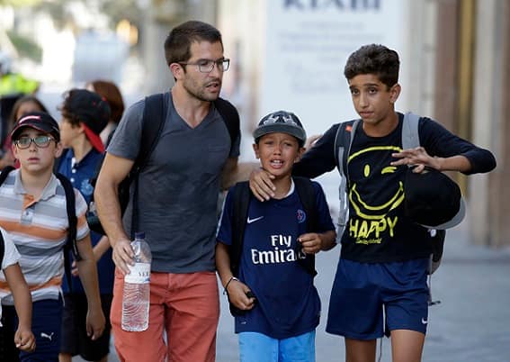 EDS NOTE : SPANISH LAW REQUIRES THAT THE FACES OF MINORS ARE MASKED IN PUBLICATIONS WITHIN SPAIN - Children, some in tears, are escorted down a road in Barcelona, Spain, Thursday, Aug. 17, 2017. Police in Barcelona say a white van has mounted a sidewalk, struck several people in the city's Las Ramblas district. (AP Photo/Manu Fernandez)