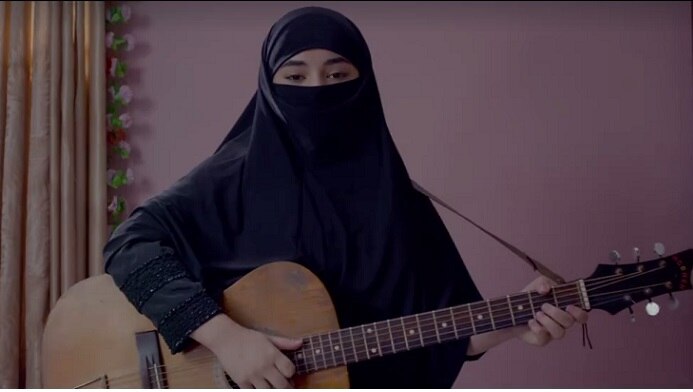 Video starts when a girl with 'Hijab' and guitar in hand introduces her first song without revealing her name.