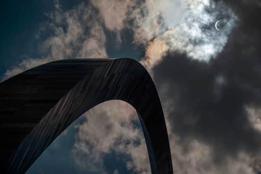 The moon begins to block the sun as a solar eclipse is seen through the clouds over the Gateway Arch, Monday, Aug. 21, 2017, in St. Louis. The Gateway Arch was just a few miles outside of the path of totality. (AP Photo/Jeff Roberson)