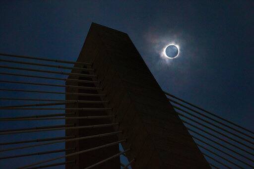 A solar eclipse shows through a layer of clouds over the Ravenel Bridge in Charleston, S.C. on Monday, Aug. 21, 2017. (Wade Spees/The Post And Courier via AP)