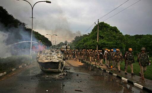 Policemen patrol past a vehicle vandalized by Dera Sacha Sauda sect members near in Panchkula, India, Friday, Aug. 25, 2017. Deadly riots have broken out in a north Indian town after a court convicted the sect's guru of raping two of his followers. Mobs also attacked journalists and set fire to government buildings and railway stations. (AP Photo/Altaf Qadri)