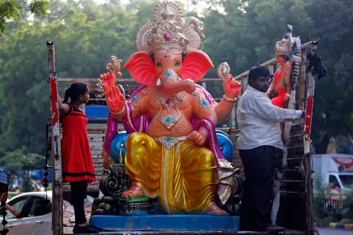 Indians travel on a truck transporting an idol of the elephant-headed Hindu god Ganesha ahead of Ganesh Chaturthi festival in Ahmadabad, India, Thursday, Aug. 24, 2017. The ten-day long Ganesha festival begins Aug. 25. (AP Photo/Ajit Solanki)
