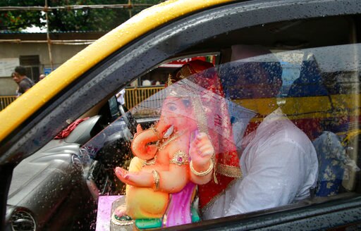 A devotee carries an idol of elephant-headed Hindu God Ganesha home in taxi for worship during Ganesh Chaturthi festival celebrations in Mumbai, India, Friday, Aug. 25, 2017. The idols will be immersed in water bodies after worship at the end of the festival. (AP Photo/Rafiq Maqbool)