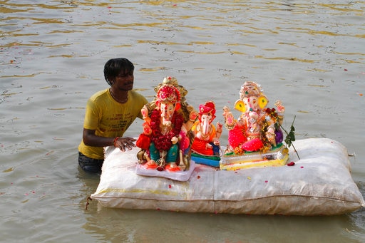 An Indian volunteer carries idols of elephant-headed Hindu god Ganesha on a makeshift raft to immerse in an artificial pond near the river Sabarmati during Ganesha Chaturthi in Ahmadabad, India, Saturday, Aug. 26, 2017. The ten-day long Ganesh Chaturthi festival celebrates the birth of Ganesha. (AP Photo/Ajit Solanki)