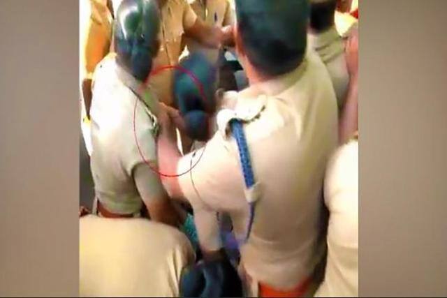 His left hand appears to be groping the female while he is trying to control the crowd.   The struggling woman, a sub inspector from Coimbatore, attempts to push away his hand over and over again but to no avail.