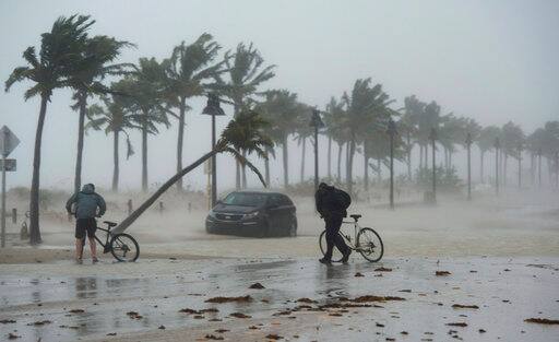 Two men walk their bicycle along a flooded street on the waterfront of Fort Lauderdale, Fla., as Hurricane Irma passes through on Sunday, Sept. 10, 2017. (Paul Chiasson/The Canadian Press via AP)