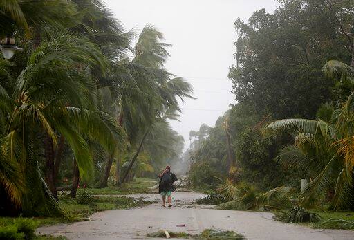 A person walks through a street lined with debris and fallen trees as Hurricane Irma passes through Naples, Fla., Sunday, Sept. 10, 2017. (AP Photo/David Goldman)