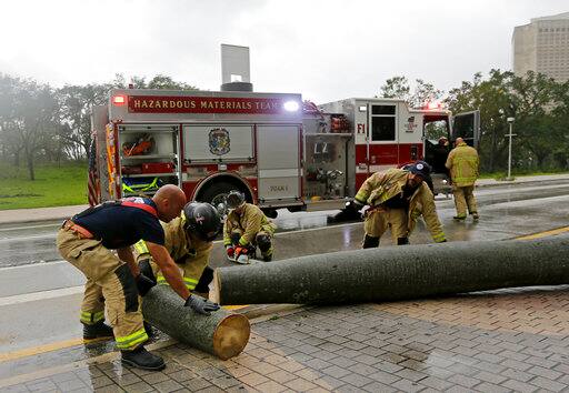 A City of Miami Fire and Rescue crew cuts up a fallen palm tree during Hurricane Irma, as they clear the street, Sunday, Sept. 10, 2017, in downtown Miami. (AP Photo/Alan Diaz)