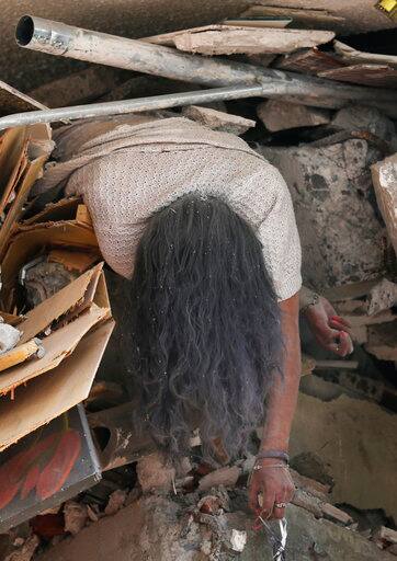 GRAPHIC CONTENT - The body of woman hangs crushed by a collapsed building in the neighborhood of Roma Norte, in Mexico City, Tuesday, Sept. 19, 2017. Throughout Mexico City, rescuer workers and residents dug through the rubble of collapsed buildings seeking survivors following a 7.1 magnitude quake. (AP Photo/Marco Ugarte)