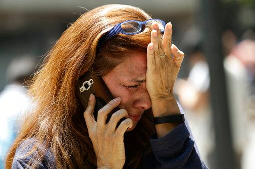 A woman cries as she tries to reach people on her cellphone after she evacuated with others to Paseo de la Reforma street after an earthquake in Mexico City, Tuesday, Sept. 19, 2017. A powerful earthquake jolted central Mexico on Tuesday, causing buildings to sway sickeningly in the capital on the anniversary of a 1985 quake that did major damage. (AP Photo/Marco Ugarte)