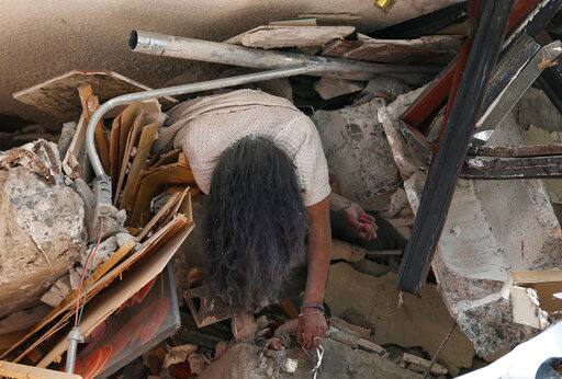 GRAPHIC CONTENT - The body of woman hangs crushed by a collapsed building in the neighborhood of Roma Norte, in Mexico City, Tuesday, Sept. 19, 2017. Throughout Mexico City, rescuer workers and residents dug through the rubble of collapsed buildings seeking survivors following a 7.1 magnitude quake. (AP Photo/Marco Ugarte)