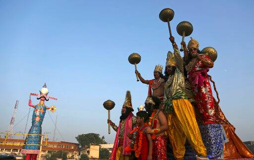 Artists dressed up as Hindu gods shout religious slogans near an effigy of demon King Ravana on the occasion of Dussehra in Jammu, India, Saturday, Sept. 30, 2017. Dussehra commemorates the triumph of Lord Rama over the demon king Ravana, marking the victory of good over evil. (AP Photo/Channi Anand)