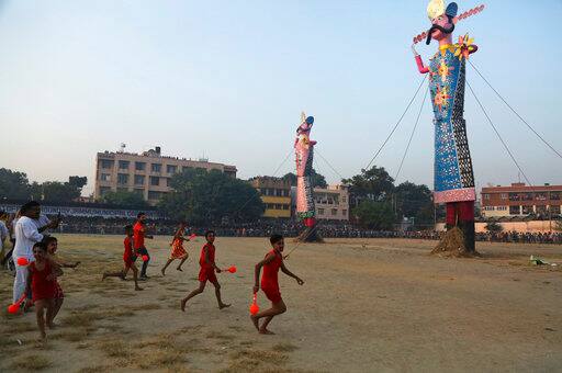 Boys run in a field where effigies of demon king Ravana have been erected to be set alight marking the end of Dussehra festival in Jammu, India, Saturday, Sept. 30, 2017. Dussehra commemorates the triumph of Lord Rama over the demon king Ravana, marking the victory of good over evil. (AP Photo/Channi Anand)