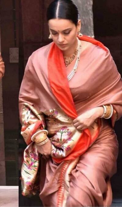 Dressed in a simple orange sari with elegant pearl jewellery, Kangana, who essays the role of the queen of Jhansi in the film, is seen walking around the set with her team. With her hair tied neatly in a bun, Kangana is looking down in the images. (Image- Twitter)