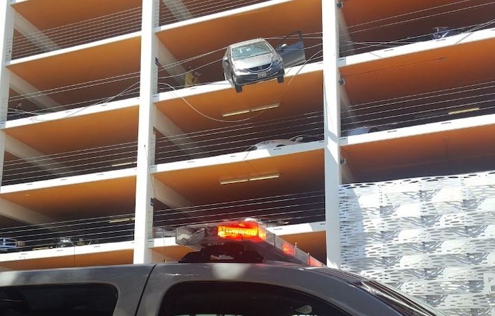 Car dangles from 4th floor parking as driver hits accelerator instead of brake Car dangles from 4th floor parking as driver hits accelerator instead of brake
