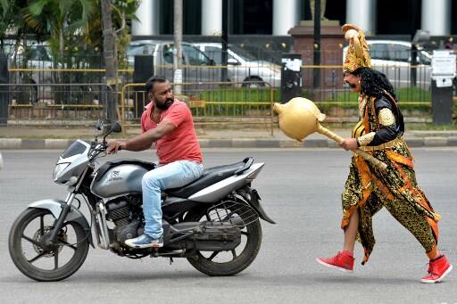 A mace-wielding 'Yamaraja,' God of Death, attired in his traditional golden dress intercepted motorists near the Town hall in Bengaluru today and warned them he would visit their homes if they flout traffic rules./ AFP PHOTO / MANJUNATH KIRAN