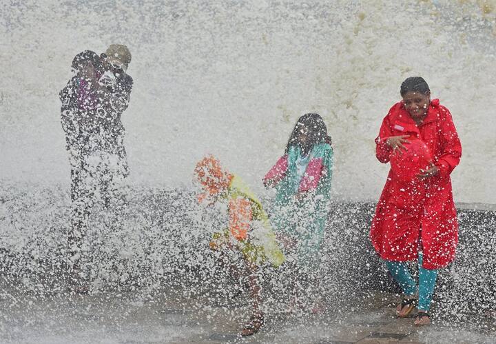 A family enjoys a high tide at the Worli sea face in Mumbai. PTI Photo