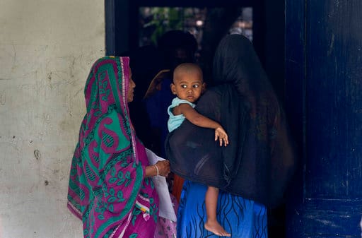 A woman carrying her child checks if their names are included in the National Register of Citizens at a draft center in Mayoung, about 55 kilometers (34 miles) east of Gauhati, India, Monday, July 30, 2018. PIC/AP.