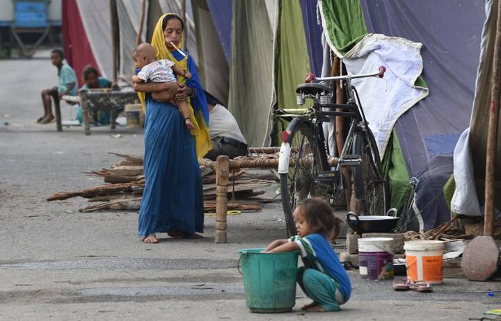Resident take shelter in a makeshift tent on higher ground as the Yamuna river flows above the danger mark in New Delhi on August 1, 2018./ AFP PHOTO