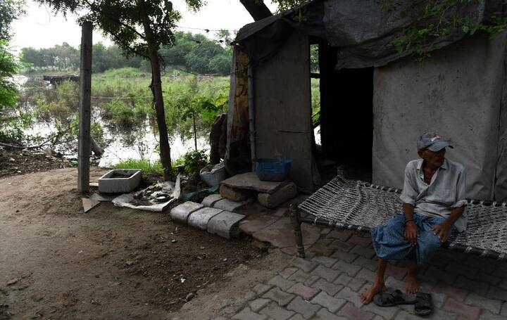 An Indian man sits near a flooded area as overflowing water from the Yamuna river encroaches due to recent heavy rainfall/ AFP