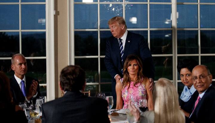 President Donald Trump walks to his seat between first lady Melania Trump, right, and Boeing Co. Chairman, President and CEO Dennis Muilenburg, left, after speaking at the dinner meeting with business leaders. (Image: AP Photo/Carolyn Kaster)
