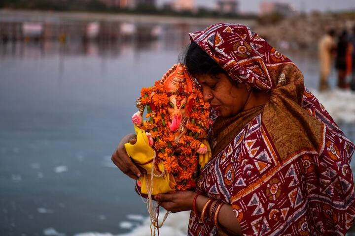 A woman prays prior to immersing an idol of Hindu god Lord Ganesh in the polluted Yamuna river on the ninth day of the eleven-day long festival Ganesh Chaturthi in New Delhi on September 21, 2018. (AFP)