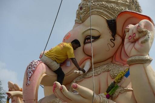 A crane worker climbs an idol of Hindu deity Ganesh to secure it before immersing it in the Hussain Sagar Lake on the eleventh day of the Ganesh Chaturthi festival in Hyderabad on September 23, 2018. (AFP)