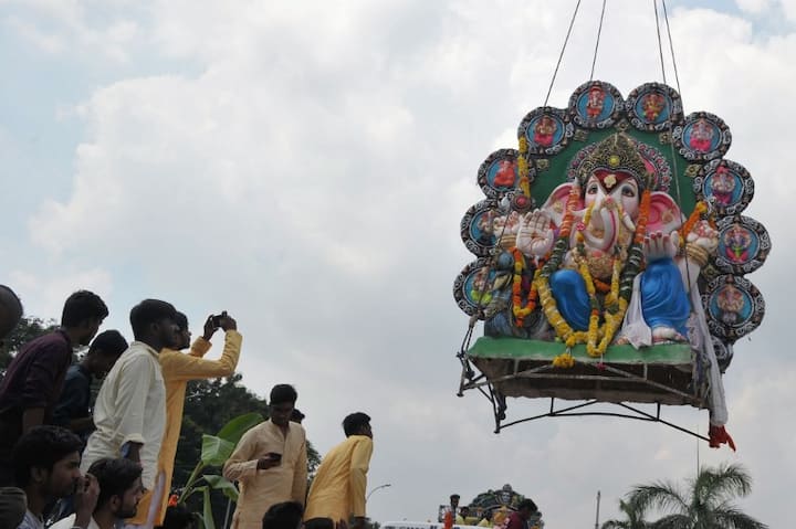 Devotees watch as crane workers lift an idol of Hindu god Lord Ganesh to immerse in the Hussain Sagar Lake on the eleventh day long festival Ganesh Chaturthi in Hyderabad on September 23, 2018.(AFP)