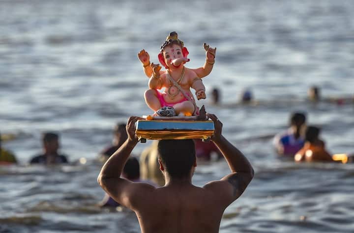 A devotee carries a Lord Ganesha idol for immersion during Ganesh Utsav celebrations at the Dadar Chawpati, in Mumbai. (PTI)