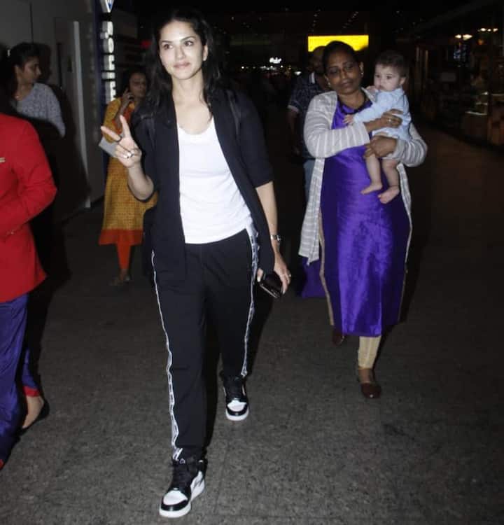Sunny wearing a black tracksuit, walked along with her babies being carried beside her by their nanny.