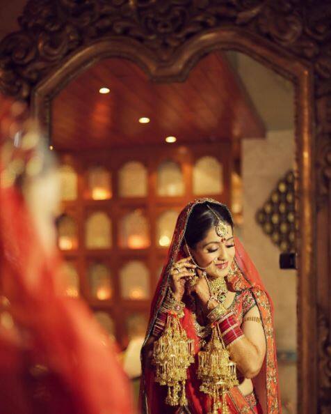Rukmini looked stunning in a traditional combination of red and orange - her lehenga is well complemented with a gold choker and maang tika(PIC CREDIT: The Wedding Story)
