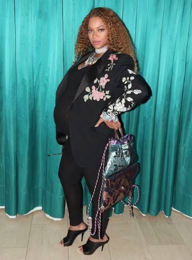 Beyonce is flaunting her growing baby bump wearing a semi-sheer fitted black T-shirt, matched withblack leggings and a black blazer embossed with pink flowers and green leaves