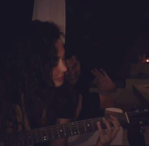 Lisa playing guitar as her husband looks on