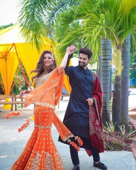 The actress dazzled in an orange sharara posing with Ravi at the mehendi event that took place last night