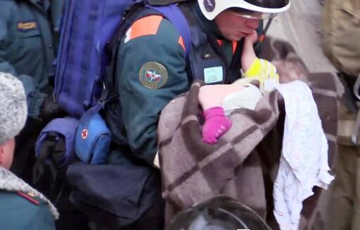 This handout picture released by The Russian Emergency Situations Ministry on January 1, 2019, shows emergency officers transporting a baby surviver after the gas explosion rocked a residential building in Russia's Urals city of Magnitogorsk. (Photo by HO / RUSSIAN EMERGENCY SITUATIONS MINISTRY / AFP) 