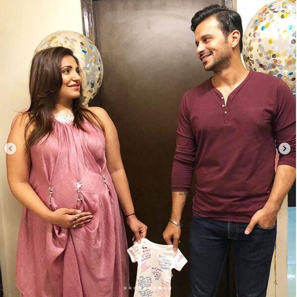 Navina and her husband Karan can be seen holding a tiny t-shirt in their hand in this photo.